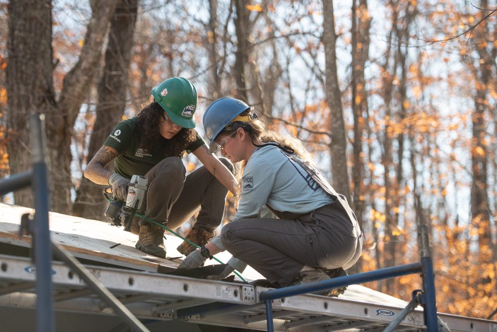 Two VYCC Corps Members doing roofing work together on scaffolding